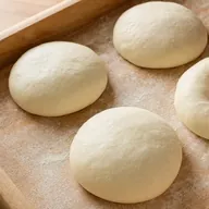 Pizza dough balls proofing in a floured tray